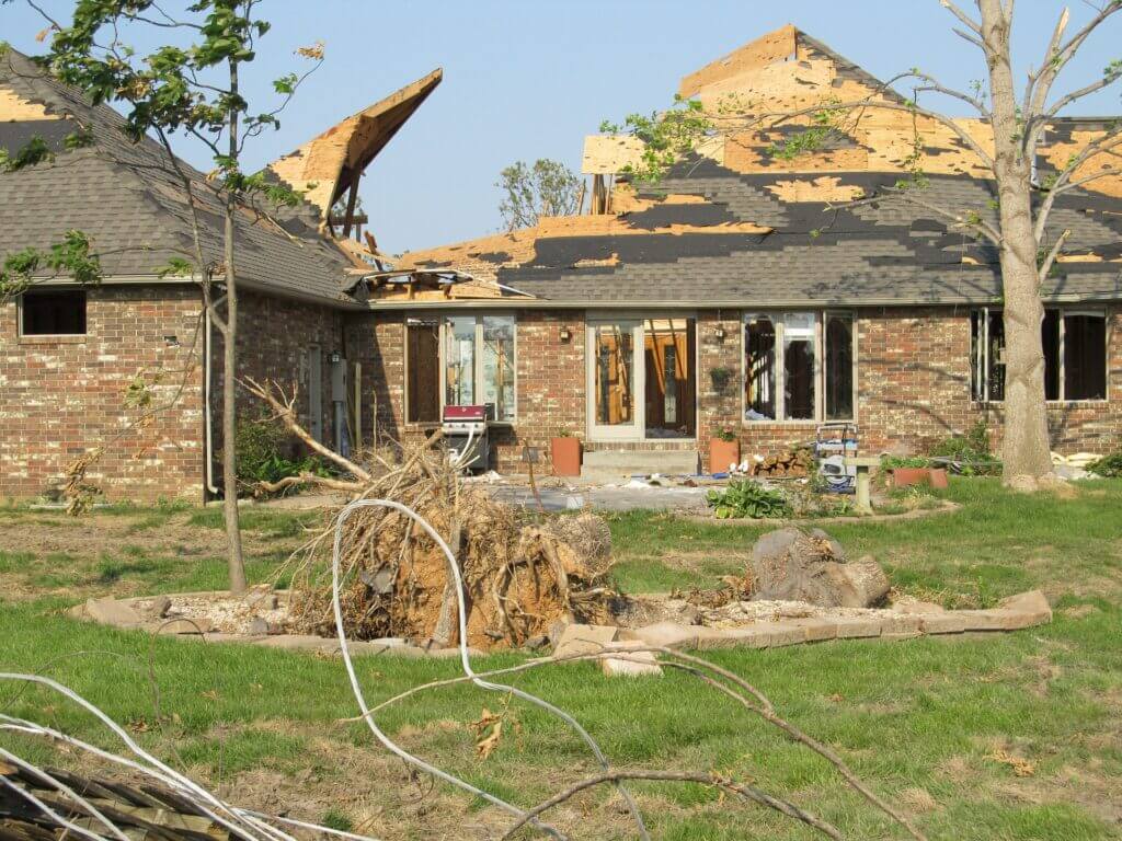 Home with storm-damaged roof and debris after severe weather